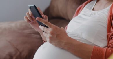 pregnant woman holding a cell phone, taking a pregnancy test using the app.